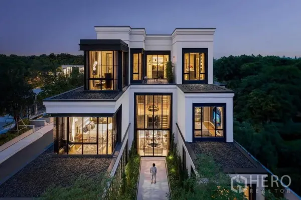 独立式住宅 出售在Saphan Sung, Bangkok - 黄昏时的三层独栋外立面，通高落地窗与景观步道。