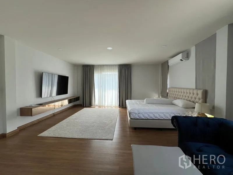 Detached House for rent in Bang Phli, Samut Prakan - Spacious master bedroom with TV wall, balcony doors and wood floor.