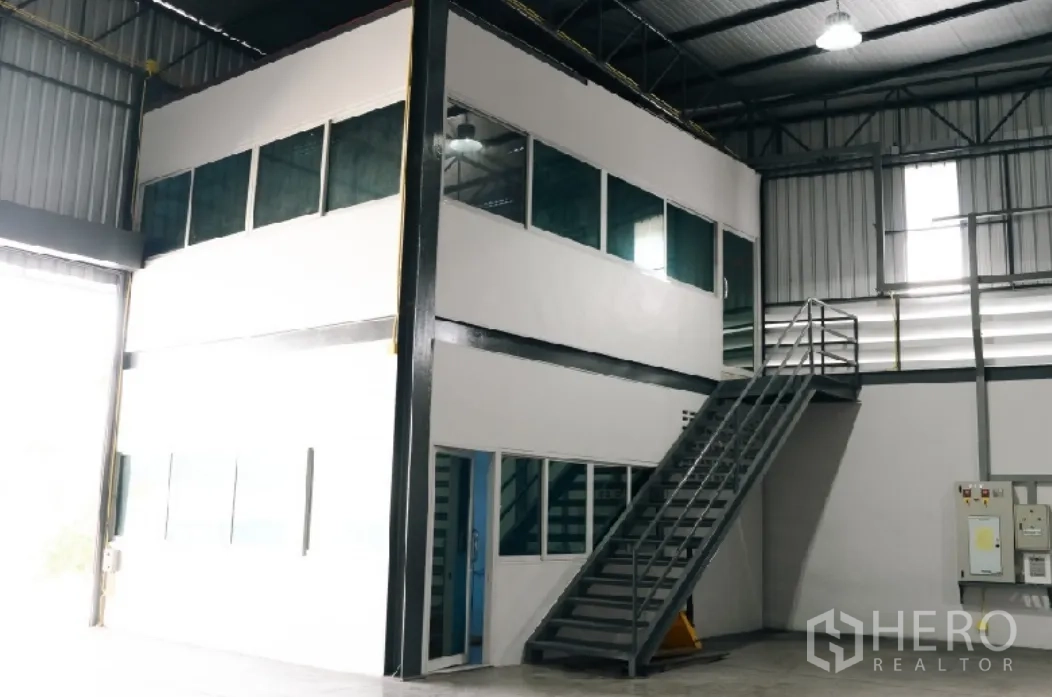 Factory for rent in Si Racha, Chon Buri - Two-storey internal office with large windows and a metal staircase inside the factory.