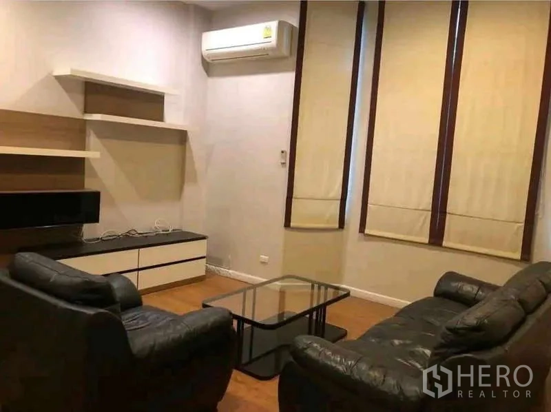 ทาวน์เฮาส์ ให้เช่าในPhra Khanong, Bangkok - ห้องนั่งเล่นพร้อมโซฟาหนัง โต๊ะกระจก และชั้นวางทีวี