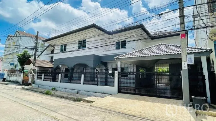 Detached House for rent in Bang Kapi, Bangkok - Two-storey detached house exterior with gated fence and roofed carport on a quiet street.