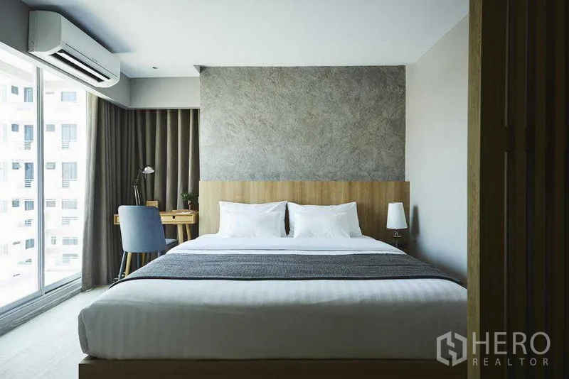 Apartment for rent in Khlong Toei, Bangkok - Modern bedroom with king bed, feature wall, desk by the window and city outlook.