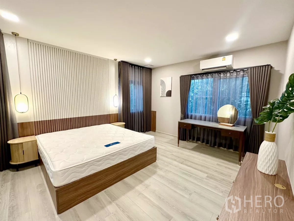 Detached House for rent in Bang Phli, Samut Prakan - Master bedroom with wood accent wall, pendant lights, and dressing table.