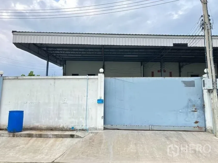 工厂 出租在Samut Prakan - 工厂入口，高混凝土围墙与金属滑门，前方有覆盖装卸雨棚