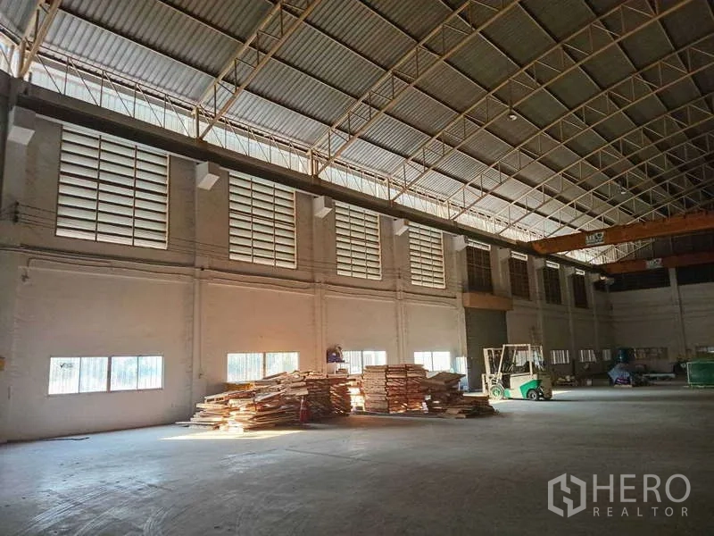 Factory for rent in Mueang Samut Prakan, Samut Prakan - Open production floor with large louver windows, skylights, and organized storage areas.