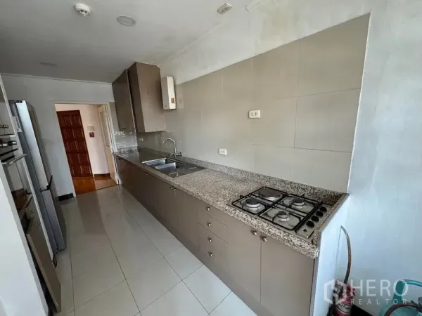 Condominium for rent in Yan Nawa, Bangkok - Galley kitchen with granite countertop, gas hob, sink and tall cabinets in a Yan Nawa condo.