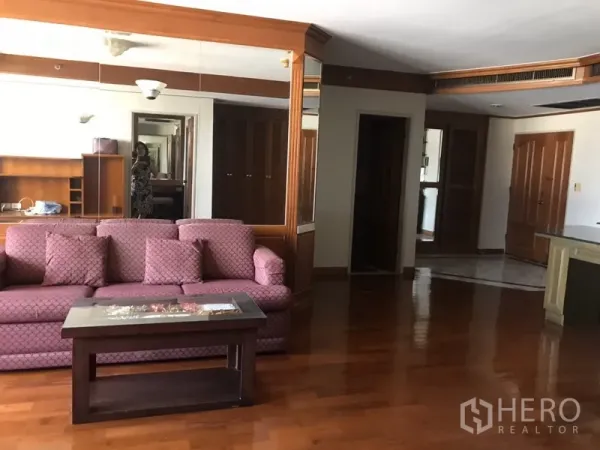 公寓 出租在Watthana, Bangkok - 宽敞起居区，粉色沙发、镜面墙板与抛光木地板。