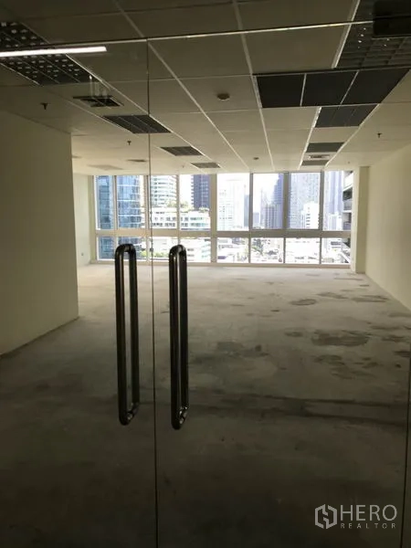 Office Space for rent in Khlong Toei, Bangkok - View through glass entry doors into a bright office with city skyline.