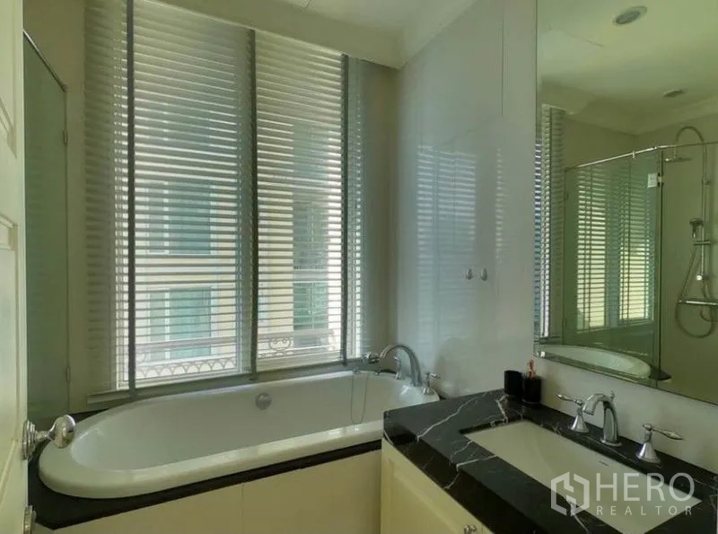 Condominium for rent in Watthana, Bangkok - Bathroom with bathtub by the window, glass shower and black stone vanity.