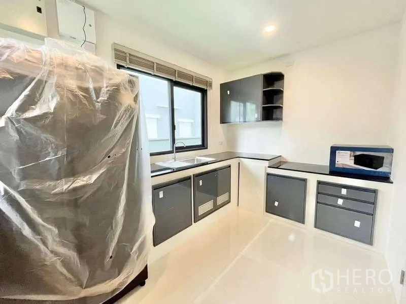 Detached House for rent in Don Mueang, Bangkok - Separate kitchen with black countertops, grey cabinetry and new appliances.