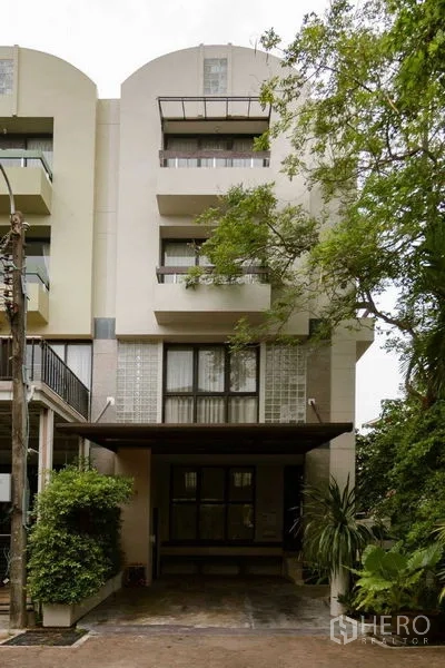 Home Office for sale in Watthana, Bangkok - Modern townhouse-style facade with balconies, covered carport and mature greenery.