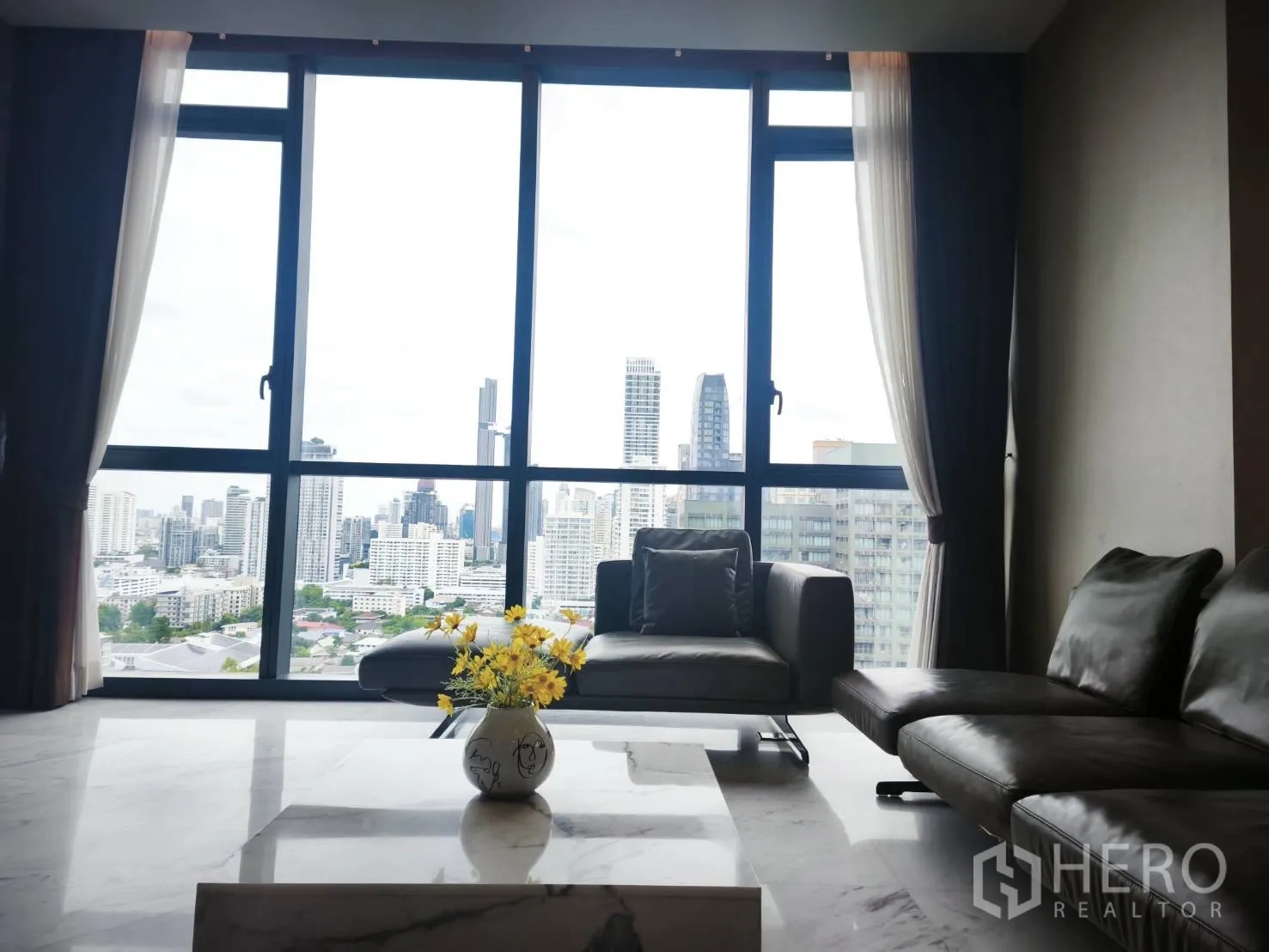 Condominium for rent in Watthana, Bangkok - Close-up of living room seating facing skyline through tall windows.