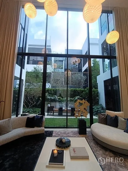 บ้าน ขาย - ห้องนั่งเล่นเพดานสูงสองชั้น กำแพงกระจกสูงจรดเพดานเปิดสู่สวนลานกลางบ้าน
