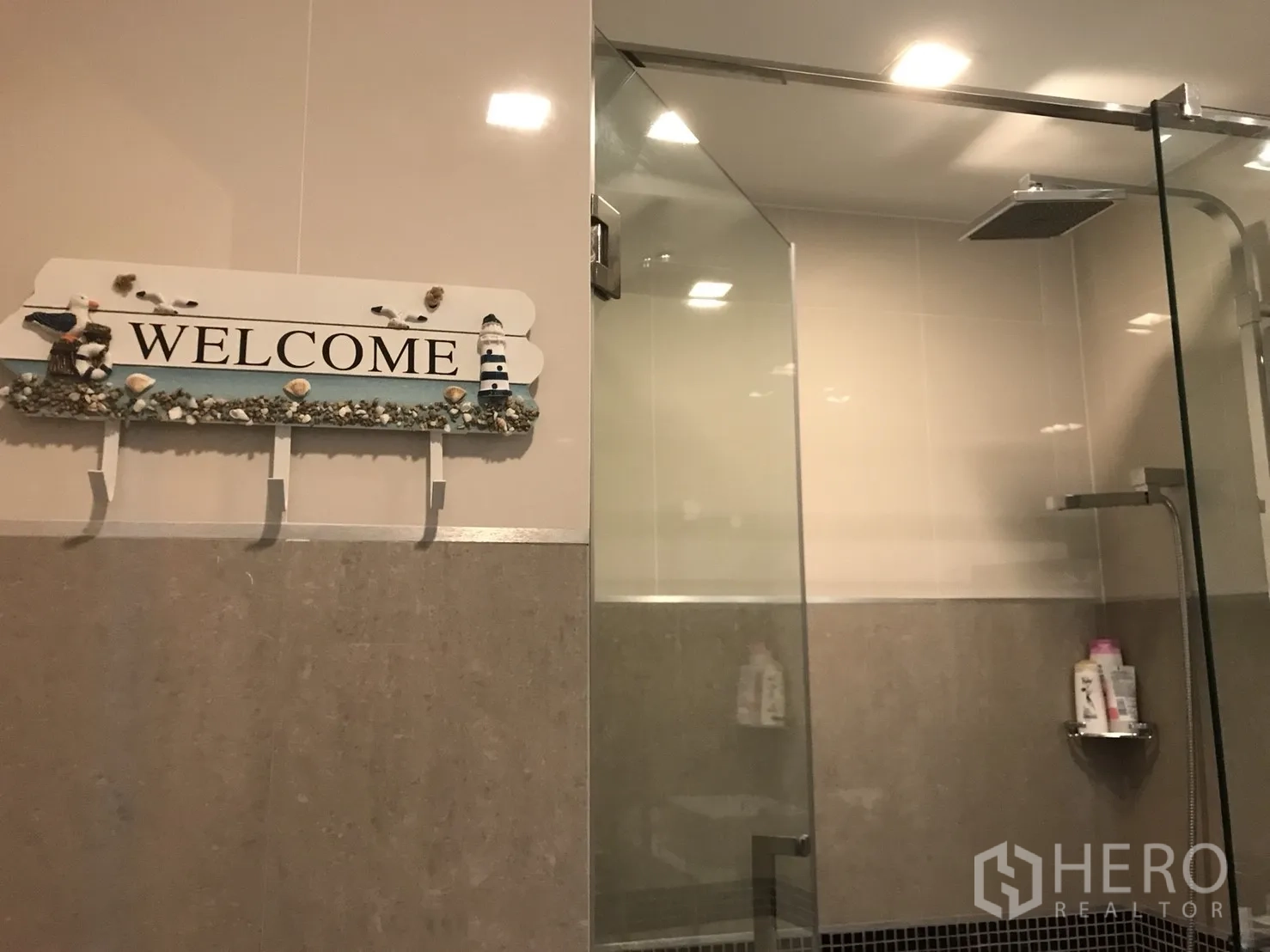 Condominium for rent in Bang Lamung, Chon Buri - Modern bathroom with glass-enclosed rain shower and warm recessed lighting.