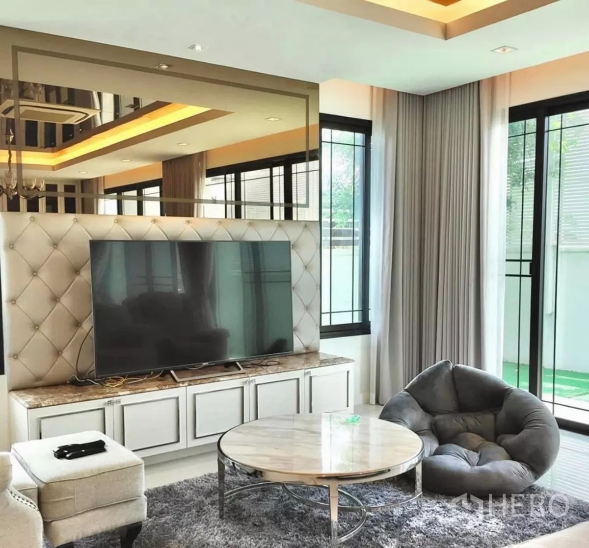 Detached House for rent in Bang Bon, Bangkok - Cozy media corner with TV console, plush chair and large sliding windows.
