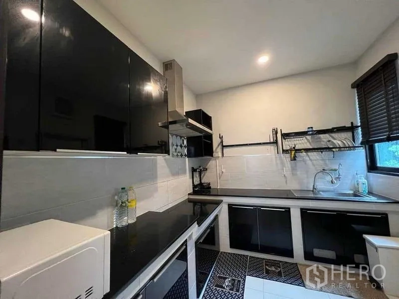 บ้าน ให้เช่าในMueang Nonthaburi, Nonthaburi - ครัวสไตล์โมเดิร์น ตู้หน้าบานเงาสีดำ พร้อมเครื่องดูดควันและหน้าต่างมุม
