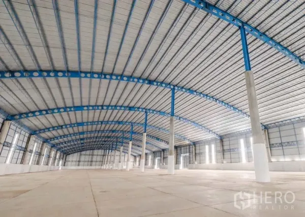 Warehouse for rent in Ban Pho, Chachoengsao - Open storage hall with ventilated metal roofing, concrete flooring, and bright sidewall panels.