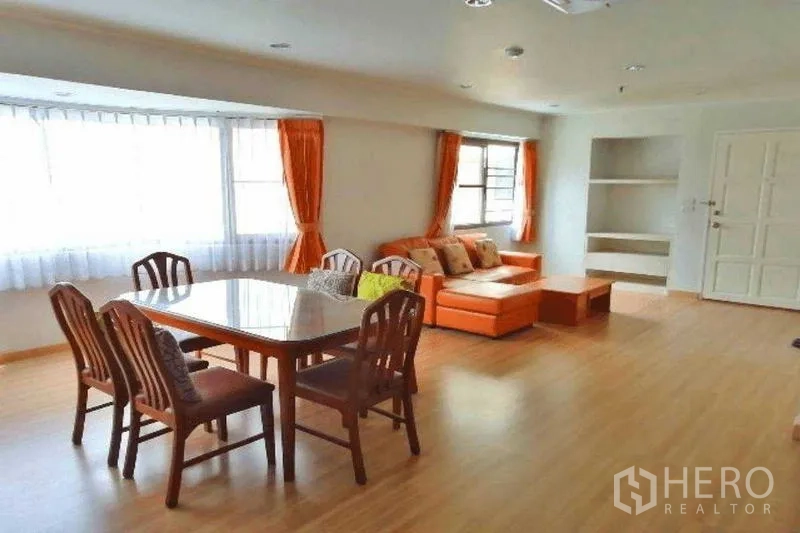 Condominium for rent in Watthana, Bangkok - Open living room featuring dining table, orange sofa and wide corner windows.