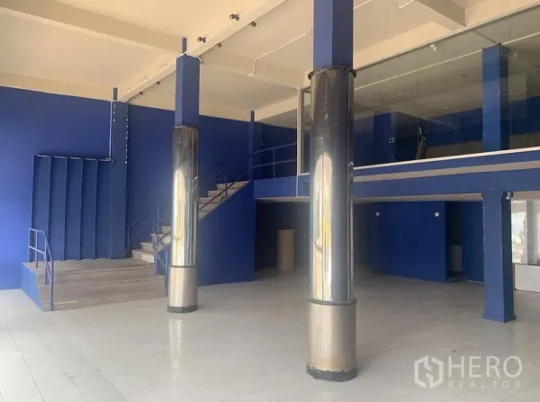 店屋 出租在Watthana, Bangkok - 挑高展厅空间，金属立柱、楼梯与玻璃夹层。