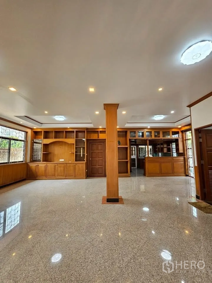 Home Office for rent in Wang Thonglang, Bangkok - Expansive ground‑floor hall with built‑in wood shelving and glossy stone flooring.