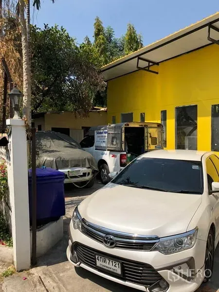 บ้าน ขายในKhlong Toei, Bangkok - ทางเข้าบ้านพร้อมที่จอดรถ หลายคัน ข้างผนังสีเหลืองสดและกันสาด
