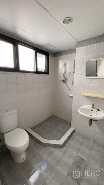 联排别墅 出租在Bang Na, Bangkok - 带窗户的浴室，角落淋浴区、坐便与小洗手盆。