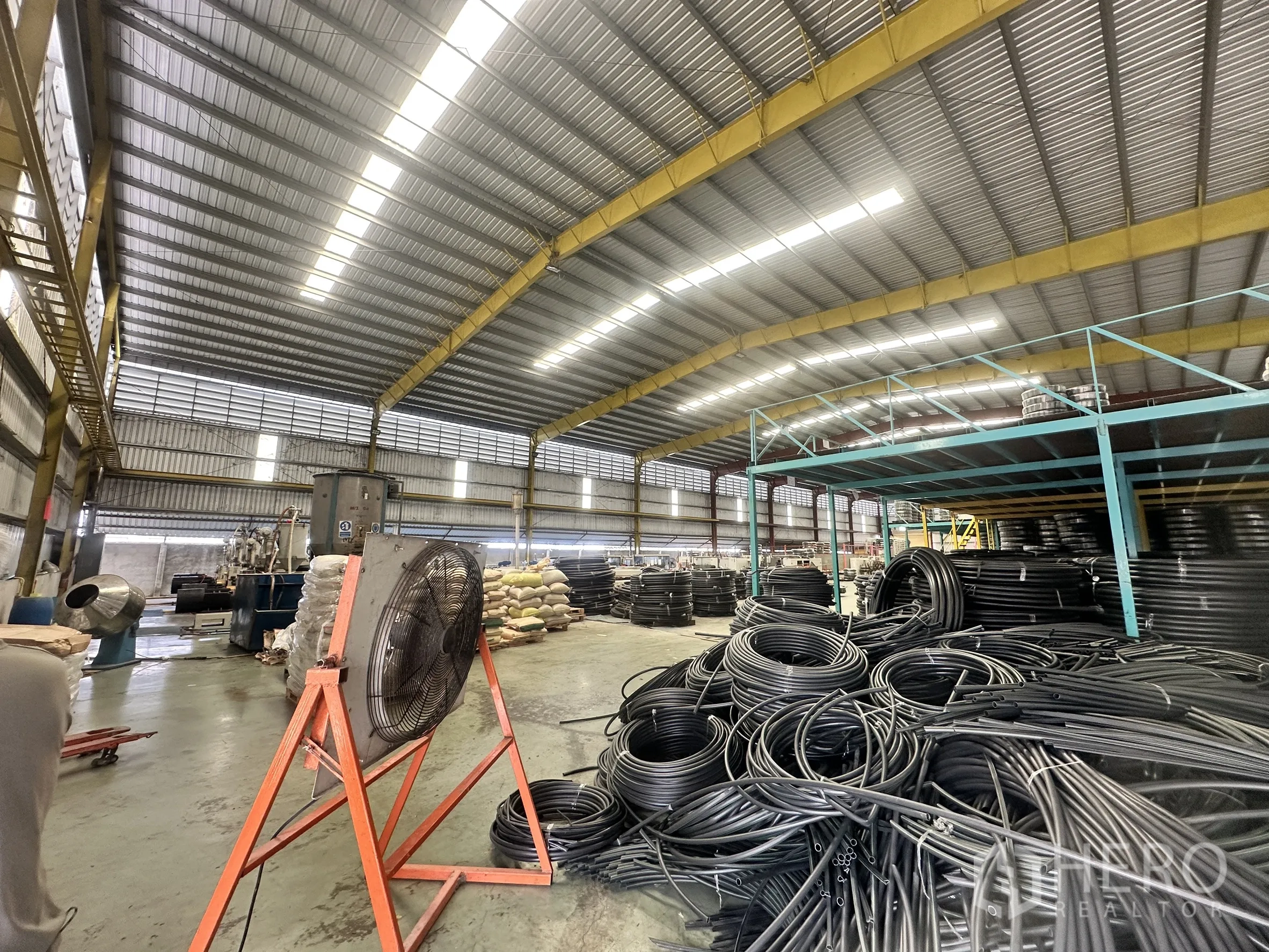 Warehouse for rent in Mueang Samut Prakan, Samut Prakan - Production area inside the warehouse with high clearance, overhead beams and materials storage.