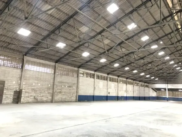 货栈 出租在Pak Kret, Nonthaburi - 仓库侧墙视角，带通风砖、上部窗带与高顶结构。