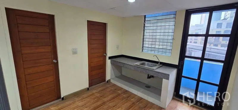 办公空间 出租 - 小型茶水区，内置水槽、木门与通向阳台的玻璃门。