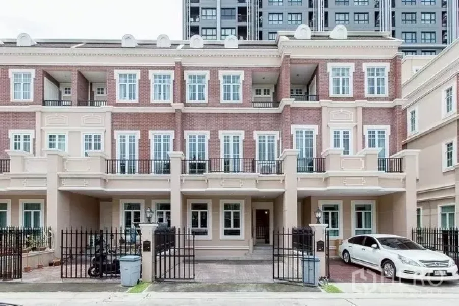 Townhouse for rent in Watthana, Bangkok - Classic multi-storey townhouse facade with brick cladding, balconies and gated parking.