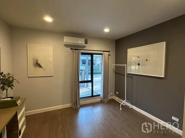 บ้าน ให้เช่าหรือขายในLam Luk Ka, Pathum Thani - ห้องชั้นล่างโปร่งสว่าง มีหน้าต่าง แอร์ และพื้นไม้.