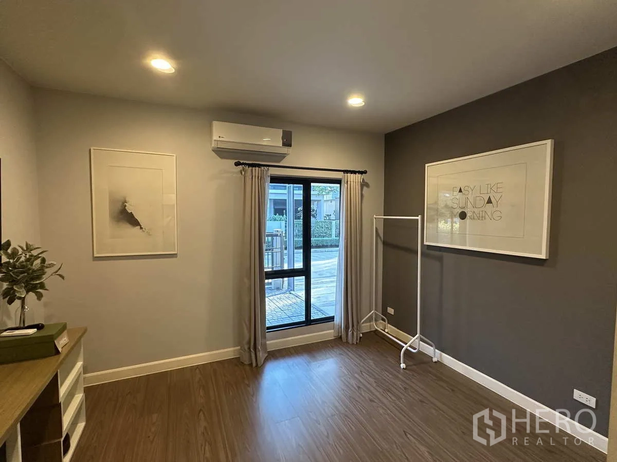 บ้าน ให้เช่าหรือขายในLam Luk Ka, Pathum Thani - ห้องชั้นล่างโปร่งสว่าง มีหน้าต่าง แอร์ และพื้นไม้.