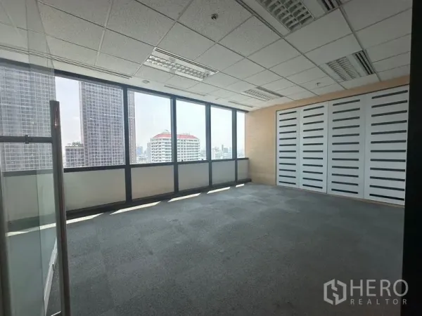 Office Space for rent in Khlong Toei, Bangkok - Private office with carpet flooring, drop ceiling lights, and full-height windows framing city views.