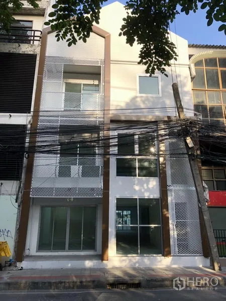 Home Office for rent in Khlong Toei, Bangkok - Front elevation featuring perforated metal screens and a double-height glass entrance.