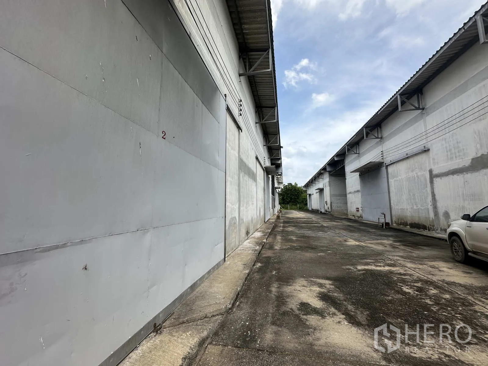 คลังสินค้า ให้เช่าในPhra Nakhon Si Ayutthaya - หน้าบย์โกดังประตูบานเลื่อนสีเทา ทางเดินคอนกรีตด้านข้าง