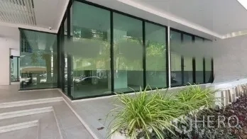 Retail Space for rent in Khlong Toei, Bangkok - Street-level retail unit with floor-to-ceiling glass facade, landscaped planters, and a covered entry in a modern building in the Sukhumvit area.
