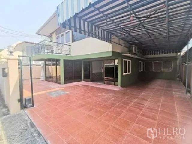 Home Office for rent in Wang Thonglang, Bangkok - Spacious front terrace with red floor tiles, striped metal canopy, balcony and sliding glass doors.
