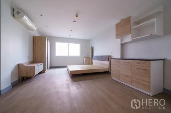 Home Office for rent in Khlong Toei, Bangkok - Large bedroom with wood flooring, platform bed, built-in cabinets and a wide window for natural light.