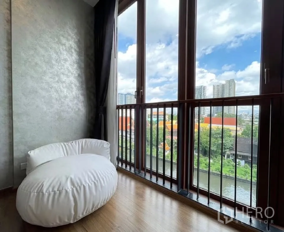 คอนโด for rent in Watthana, Bangkok - มุมนั่งพักพร้อมบีนแบ็กสีขาวข้างหน้าต่างสูงมองเห็นวิวคลองและอาคารสูง