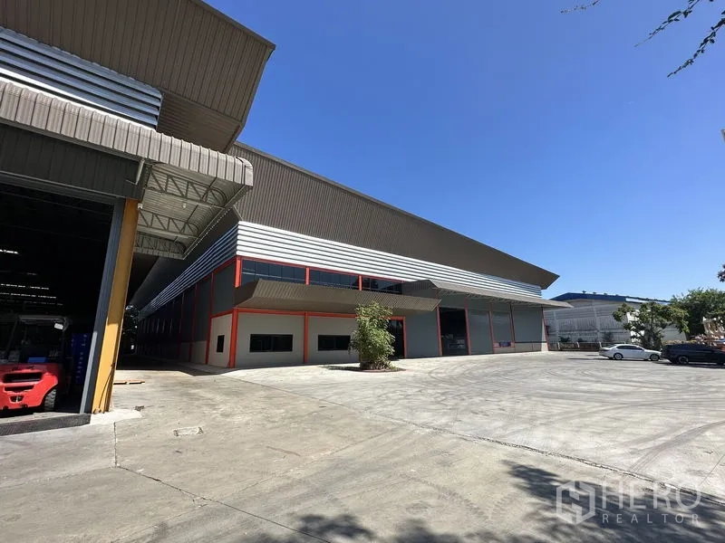Factory for rent in Chachoengsao - Angled view of a large steel‑clad factory building with office block and expansive truck turning space.