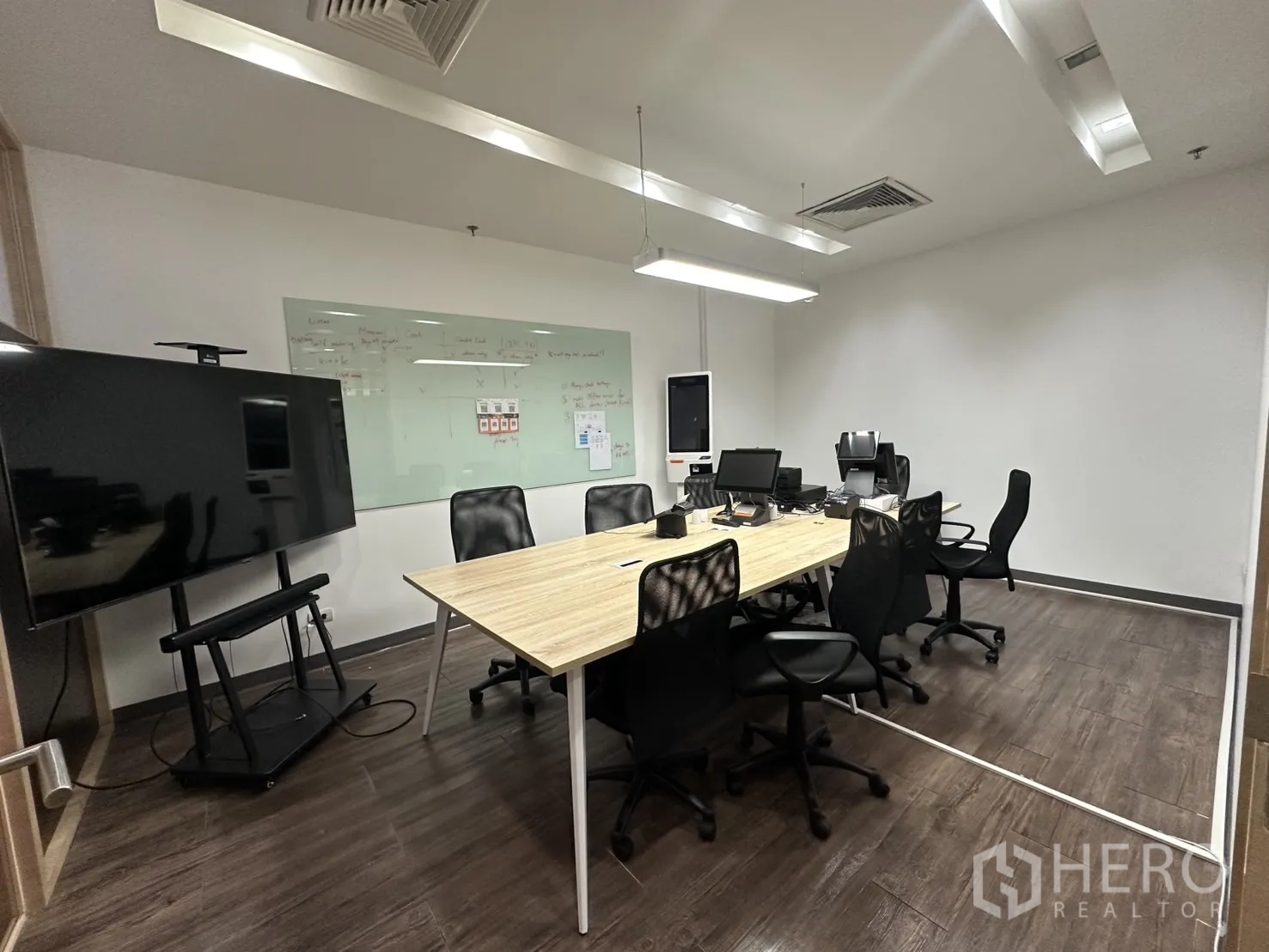 Office Space for rent - Conference room featuring presentation screen, whiteboard, and seating for ten.