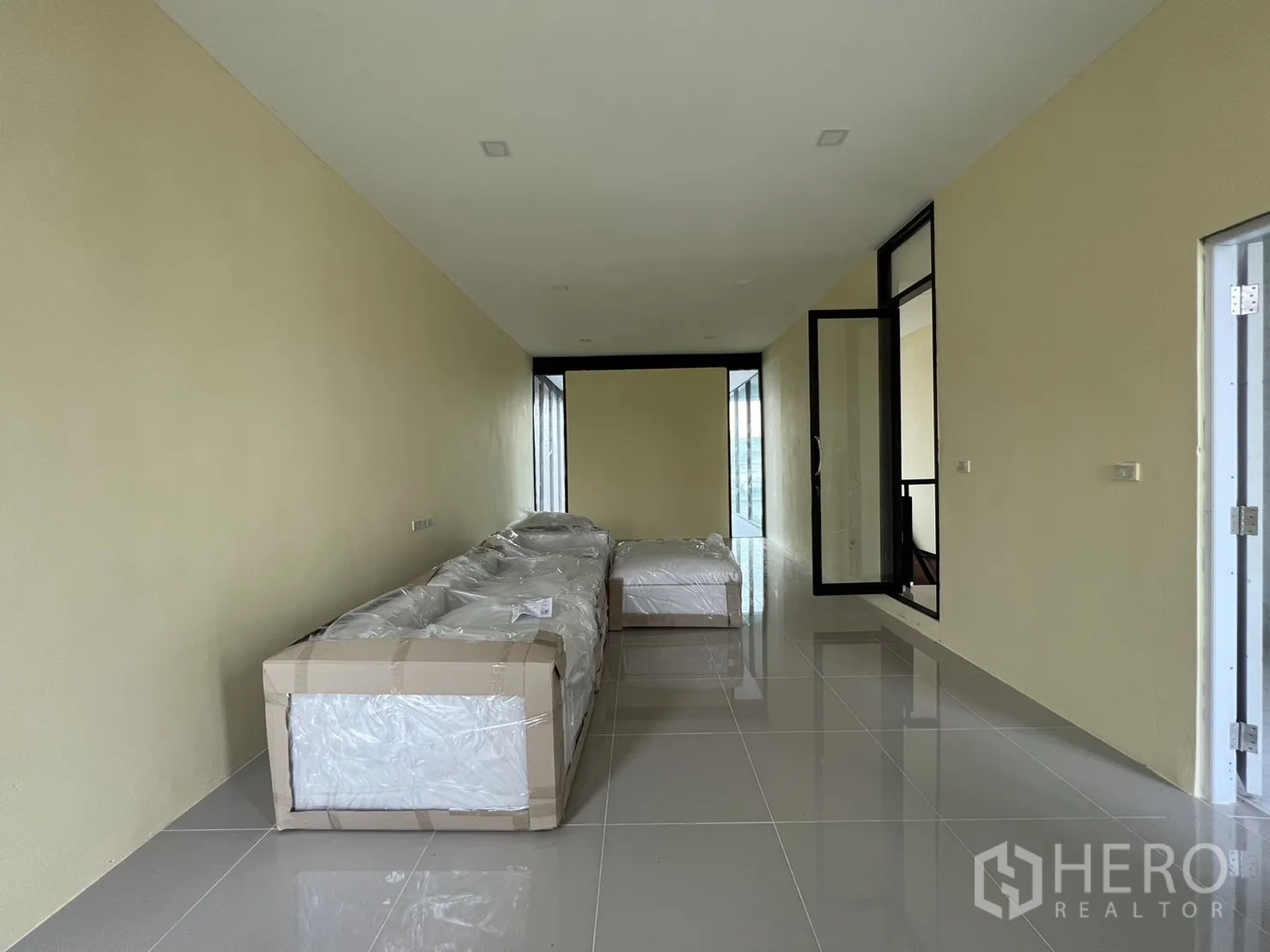 บ้าน ให้เช่าหรือขายในPhra Khanong, Bangkok - อีกมุมของห้องยาวพร้อมโซฟาห่อและพื้นกระเบื้อง