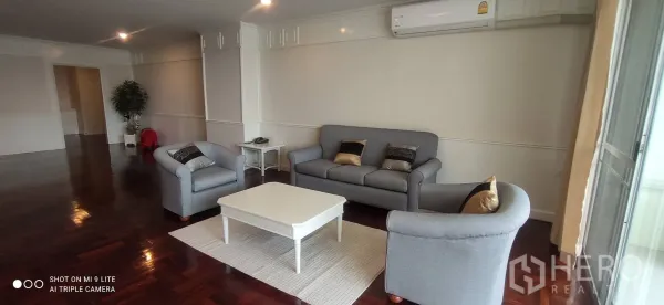 อพาร์ทเมนท์ ให้เช่าในWatthana, Bangkok - มุมนั่งเล่นอบอุ่น โซฟาและเก้าอี้สองตัว โต๊ะกลางสีขาว พื้นไม้ขัดเงา