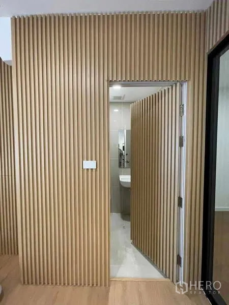 Townhouse for rent or sale in Bang Kapi, Bangkok - Doorway set in slatted wood wall opening to a modern bathroom.