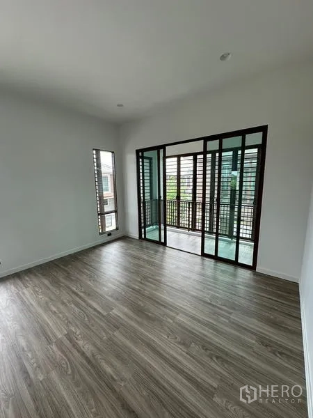 Detached House for rent in Bang Kapi, Bangkok - Upstairs room with sliding glass doors opening to a balcony with wooden louver screens.