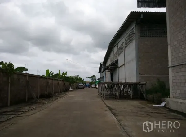 Factory for rent or sale in Krathum Baen, Samut Sakhon - Wide internal road beside a large factory warehouse with loading bay and parking in Krathum Baen, Samut Sakhon.
