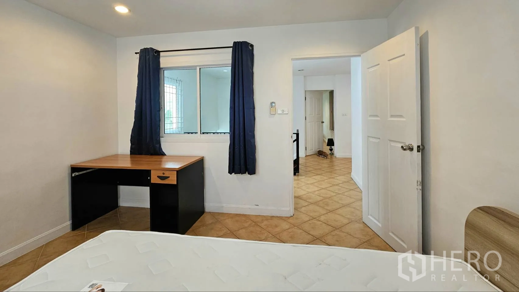 Detached House for rent in Saphan Sung, Bangkok - Bedroom with white walls, a desk, window with dark curtains, and tiled flooring.