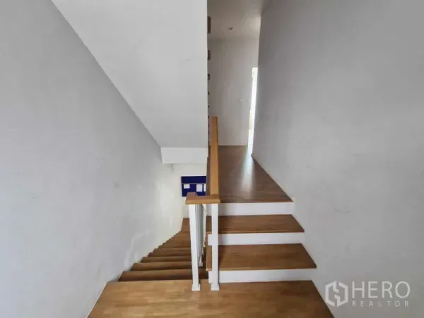 联排别墅 出售在Phra Pradaeng, Samut Prakan - 采光良好的楼梯间，木质台阶与白色扶手