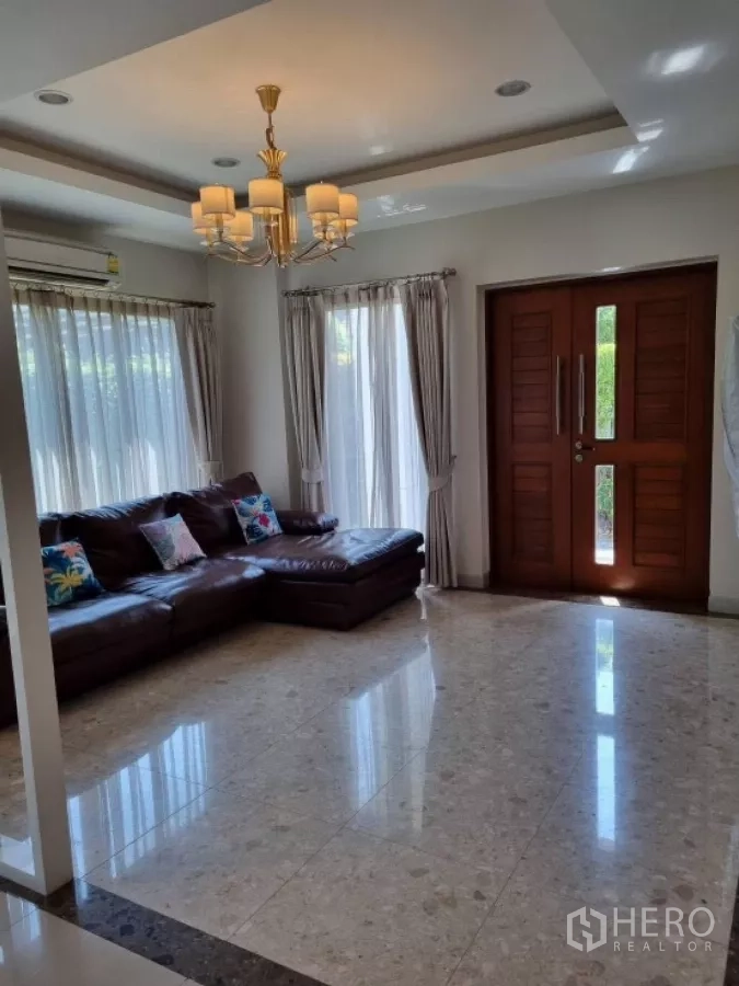 บ้าน ให้เช่าในMueang Nonthaburi, Nonthaburi - ห้องนั่งเล่นกว้าง โคมแชนเดอเลียร์ โซฟาหนัง และประตูไม้บานคู่