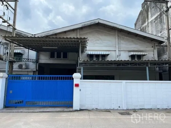 Warehouse for rent in Khlong Toei, Bangkok - Street-facing warehouse facade with blue sliding gate and white perimeter wall.